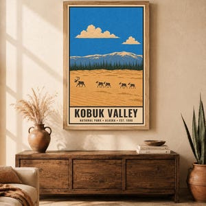 Pu&ograve; includere: Una stampa artistica rettangolare da parete con un'illustrazione paesaggistica del Parco Nazionale della Kobuk Valley in Alaska. La scena raffigura un terreno sabbioso color marrone chiaro con un branco di carib&ugrave;, una foresta verde scuro e montagne innevate.