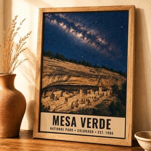 May include: A framed wall art print featuring a night sky filled with stars above the cliff dwellings of Mesa Verde National Park. The print includes the text MESA VERDE NATIONAL PARK COLORADO EST. 1906 in a clean, black sans-serif font at the bottom.