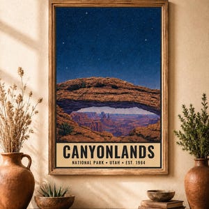 May include: A framed rectangular wall art print featuring a night sky over the Mesa Arch in Canyonlands National Park, Utah. The text reads CANYONLANDS NATIONAL PARK &bull; UTAH &bull; EST. 1964. The image depicts a natural rock arch framing a canyon.