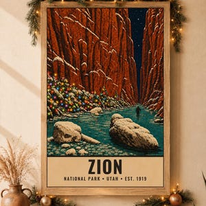 May include: A framed vertical poster depicting a snowy Zion National Park canyon at night with a river, large rocks, and a lone hiker. The scene features a tree decorated with colorful lights. The text reads ZION NATIONAL PARK UTAH EST. 1919.