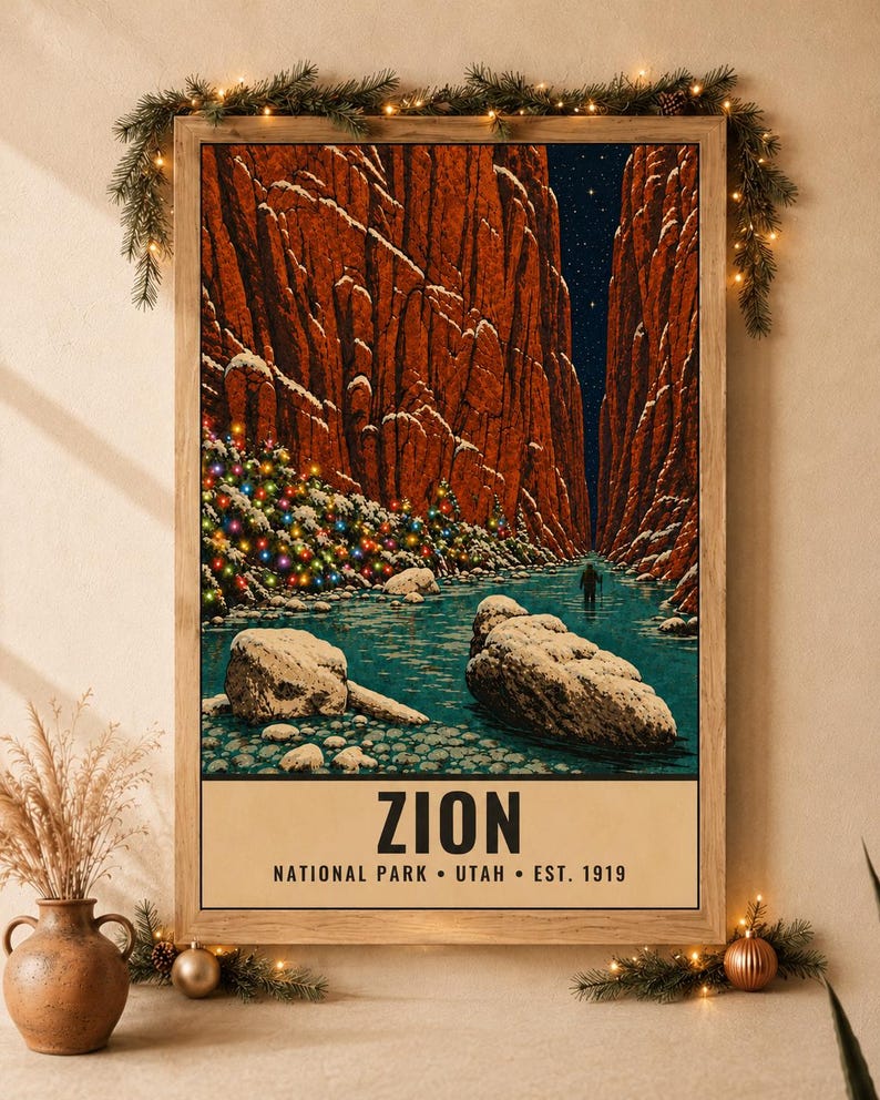 May include: A framed vertical poster depicting a snowy Zion National Park canyon at night with a river, large rocks, and a lone hiker. The scene features a tree decorated with colorful lights. The text reads ZION NATIONAL PARK UTAH EST. 1919.