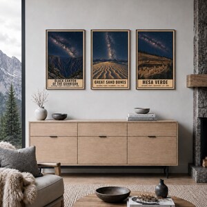 May include: Three vertical framed wall art prints featuring night sky landscapes of Black Canyon of the Gunnison, Great Sand Dunes, and Mesa Verde National Parks. Each print displays a starry galaxy above the park terrain with text below.