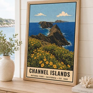 May include: A framed vertical poster featuring a landscape illustration of Channel Islands National Park, California. The artwork depicts rocky cliffs, deep blue ocean waters, and yellow wildflowers under a light blue sky with white clouds.