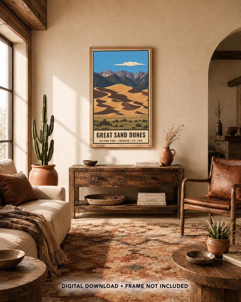 K&ouml;nnte beinhalten: Ein vertikaler Wandkunstdruck mit einer Landschaftsillustration des Great Sand Dunes Nationalparks in Colorado. Das Kunstwerk zeigt goldene Sandd&uuml;nen, dunkelgr&uuml;ne Berge und einen blauen Himmel mit einer Wolke. Der Text lautet: GREAT SAND DUNES NATIONAL PARK &bull; COLORADO &bull; EST. 2004.
