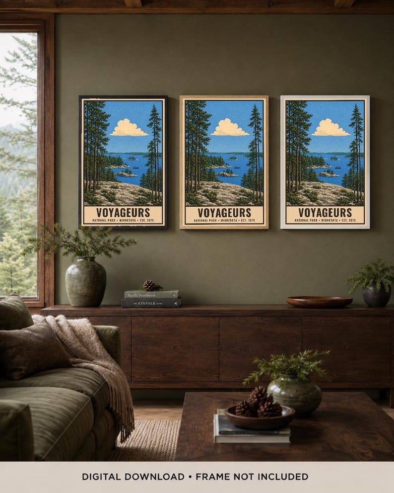Op de afbeelding: Drie identieke verticale wandkunstprints met een landschap van Voyageurs National Park, Minnesota. Elke print toont een blauw meer, een rotsachtige kustlijn, hoge dennenbomen en een wolk, met de tekst VOYAGEURS NATIONAL PARK MINNESOTA EST. 1975.