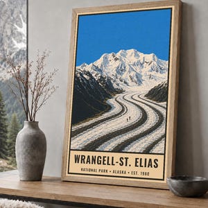 K&ouml;nnte beinhalten: Ein vertikales rechteckiges Poster mit einer Landschaftsillustration des Wrangell-St. Elias Nationalparks in Alaska. Das Kunstwerk zeigt ein schneebedecktes Gebirge und einen gewundenen Gletscher. Der Text lautet WRANGELL-ST. ELIAS NATIONAL PARK ALASKA EST. 1980.