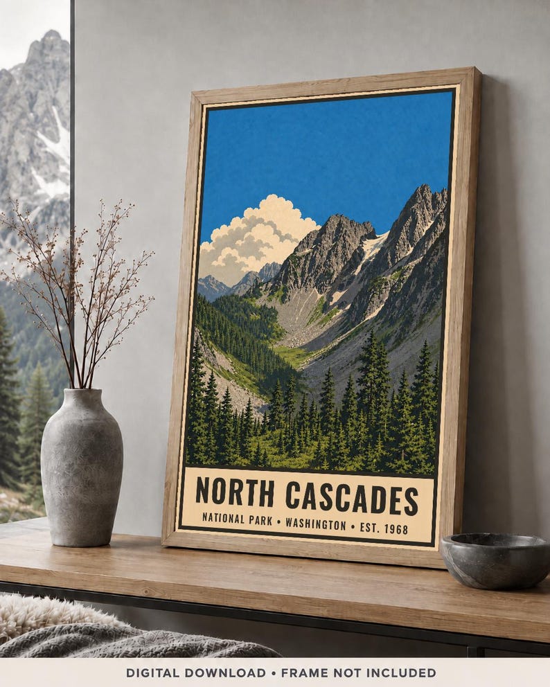 Op de afbeelding: Een ingelijste verticale poster met een gestileerde illustratie van het North Cascades National Park in Washington. Het kunstwerk toont grillige bergtoppen, een dicht naaldbos en een grote witte wolk tegen een helderblauwe lucht.