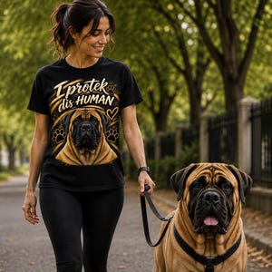 May include: A black short-sleeved t-shirt featuring a graphic of a tan and black Mastiff dog face, paw prints, a heart, and the text "I protek dis HUMAN" in gold lettering. The shirt is paired with black leggings and a black dog leash.