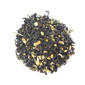May include: A close-up of a blend of black tea leaves, green tea leaves, and dried citrus peel. The tea leaves are a dark brown color and the citrus peel is a light yellow color.