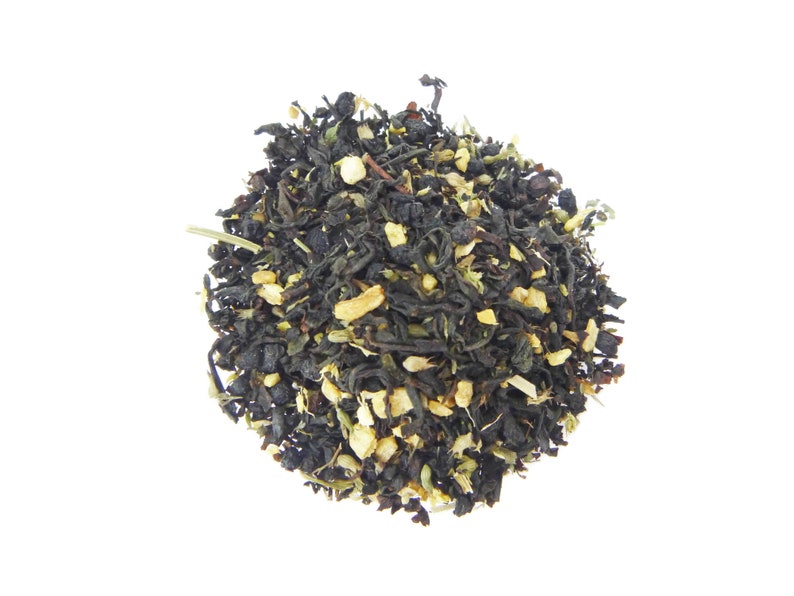 May include: A close-up of a blend of black tea leaves, green tea leaves, and dried citrus peel. The tea leaves are a dark brown color and the citrus peel is a light yellow color.