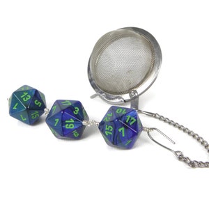 May include: A silver tea infuser with a chain and three blue and green iridescent dice attached to it.