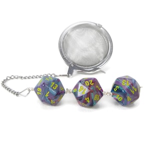 May include: A silver tea infuser with a chain and three purple and teal dice with yellow numbers. The dice are connected to the chain with silver beads.