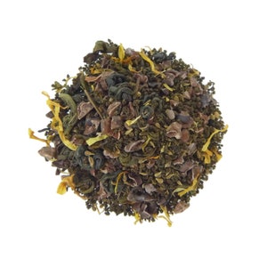 May include: A close-up of a blend of green tea, cocoa nibs, and dried mango pieces. The tea is a loose leaf blend and is ready to be brewed.