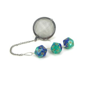 May include: A silver tea infuser with a chain and three blue and green dice attached. The dice are numbered 1-20.