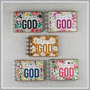 May include: Five spiral-bound notebooks featuring floral or daisy patterns and the text This is our GOD. The covers display various color schemes including pink, red, green, yellow, and blue, with white wire binding on the left side of each item.