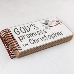 May include: A personalized notebook with the text "GOD'S promises for Christopher" in black script. The cover features a watercolor illustration of two birds on a branch. The notebook has a brown spiral binding.