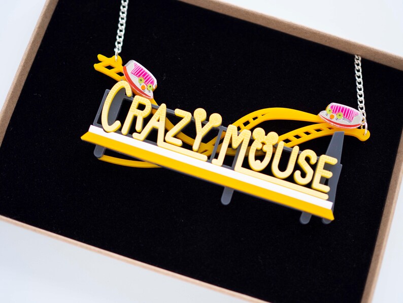 May include: A yellow and black necklace with a roller coaster design and the words "Crazy Mouse".