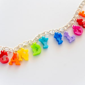 Puede incluir: Un collar de cadena plateada con abalorios de letras de colores arco&iacute;ris que deletrean "CANDY FLOSS".
