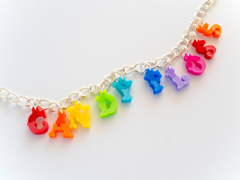 Puede incluir: Un collar de cadena plateada con abalorios de letras de colores arco&iacute;ris que deletrean "CANDY FLOSS".
