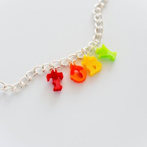 Puede incluir: Un collar de cadena plateada con abalorios de letras de colores que deletrean la palabra "TODAY". Los abalorios son rojos, naranjas, amarillos y verdes.