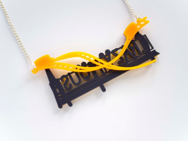 May include: A black and yellow necklace with a roller coaster design. The necklace features the words "Crazy Mouse" on the roller coaster.
