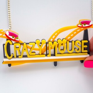 May include: A yellow and black necklace with a roller coaster design and the words "Crazy Mouse".