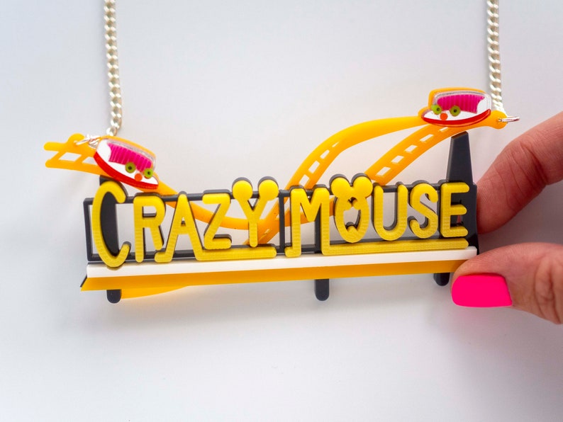 May include: A yellow and black necklace with a roller coaster design and the words "Crazy Mouse".