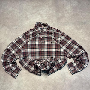 May include: A long-sleeve button-down shirt featuring a plaid pattern in shades of dark red, navy blue, white, and green. The shirt has a pointed collar, a front button placket, and a small dark embroidered logo on the left chest area.