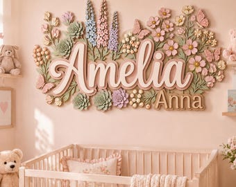 May include: A wall-mounted wooden sign featuring the names Amelia and Anna in raised lettering, surrounded by a decorative arrangement of sculpted flowers, leaves, butterflies, and succulents in shades of pink, green, blue, and cream.