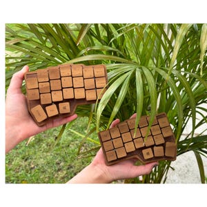 May include: A split ergonomic computer keyboard featuring two separate wooden halves with brown keycaps. Each half has a contoured, non-standard layout with engraved letters and symbols on the keys, including Enter, Fn, and Windows keys.