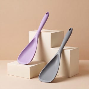 May include: Two kitchen rice paddles, one in a light lavender purple and one in a solid grey, each featuring a wide, curved scoop head and a long, slender handle with a circular hole at the top for hanging, constructed from a smooth, matte material.