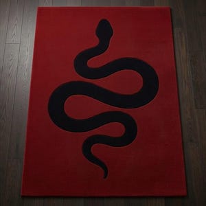 Puede incluir: Una alfombra rectangular que presenta un fondo rojo intenso sólido con una gran silueta de serpiente negra centrada. La serpiente se muestra en una postura sinuosa en forma de S, extendiéndose verticalmente por el centro de la alfombra.