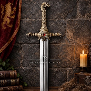 Può includere: Una spada decorativa con impugnatura in metallo dorato, pomolo e guardia a forma di testa di lupo, impreziosita da una gemma rossa centrale. La lama dritta in acciaio presenta l'incisione NORSEMEN BLADES al centro.