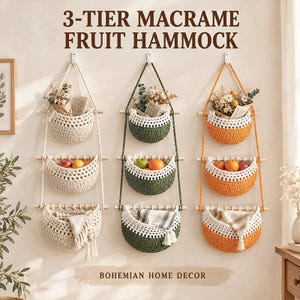 May include: Three 3-tier macrame fruit hammocks hanging on a wall. Each unit features three woven baskets in cream, green, and orange, suspended by wooden dowels and ropes. The baskets contain dried flowers, fresh fruits, and folded fabric textiles.