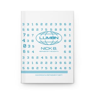 May include: A white notebook with a blue design featuring the word "LUMON" inside a globe graphic. The notebook also has the text "NICK B. REFINER OF THE MONTH" and a series of numbers. The bottom of the notebook reads "MACRODATA REFINEMENT DEPT."