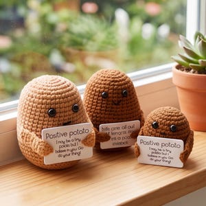 Puede incluir: Tres figuras de patata tejidas a ganchillo en varios tonos de marrón con ojos de cuentas negras. Cada figura sostiene un cartel rectangular blanco. Los dos carteles exteriores dicen Positive potato, I may be a tiny potato but I believe in you.