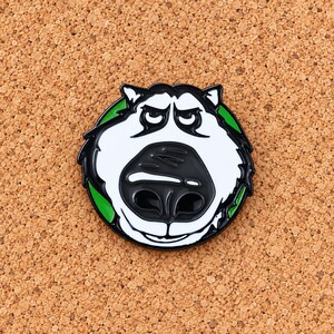 May include: A circular enamel pin featuring a stylized graphic of a dog face with a large black nose, white fur, and black outlines. The design is set against a vibrant green circular background, creating a high-contrast look for this accessory.