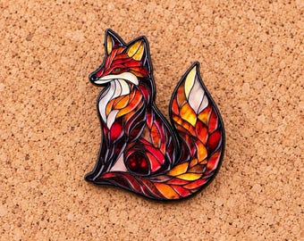 Puede incluir: Un broche de esmalte con forma de zorro que presenta un diseño estilo vidriera con contornos de metal negro. El zorro está coloreado en tonos vibrantes de naranja, rojo, amarillo y blanco, representado sentado con su cola tupida enroscada.