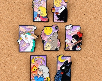 Puede incluir: Una colección de siete pines de esmalte rectangulares con coloridas ilustraciones de dibujos animados de varios personajes sobre fondos pastel, incluyendo un dragón, un gato negro, una criatura gris y figuras humanas, todos con bordes de metal dorado.