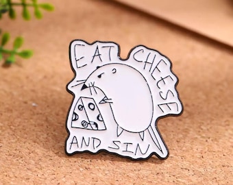 Puede incluir: Un pin de esmalte blanco con contornos negros que muestra un ratón de dibujos animados junto a un trozo de queso suizo. El texto EAT CHEESE AND SIN está escrito en letras negras alrededor del ratón. El pin tiene una forma orgánica irregular.
