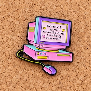 Peut inclure: Une broche en émail rose et violet en forme d'ordinateur de bureau vintage avec un écran et une base clavier. L'écran affiche le texte 'None of your emails are finding me well' entouré de petits cœurs jaunes et roses et d'une souris.