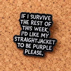 Op de afbeelding: Een zwarte emaille speld met een geschulpte rand met de witte tekst: IF I SURVIVE THE REST OF THIS WEEK, I'D LIKE MY STRAIGHTJACKET TO BE PURPLE PLEASE. De speld heeft een glanzende afwerking en een vorm die de tekst nauwkeurig volgt.