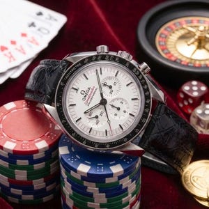 Peut inclure: Une montre chronographe Omega Speedmaster Professional en argent avec un cadran blanc, une lunette tachymétrique noire et un bracelet en cuir noir. Le cadran présente trois sous-cadrans, des aiguilles noires et le texte Omega Speedmaster Professional.
