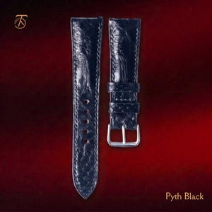 May include: A black watch strap with a textured, scale-like pattern and a glossy finish. The strap features a silver-toned metal buckle and two matching keepers. The text Pyth Black is visible in the bottom right corner of the image.