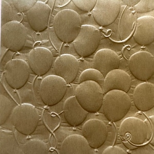 May include: A sheet of textured parchment paper with a pattern of embossed balloons. The paper is a light brown color and has a rough, textured surface. The text "Textured Parchment Paper" and "Balloons" is printed on the paper.