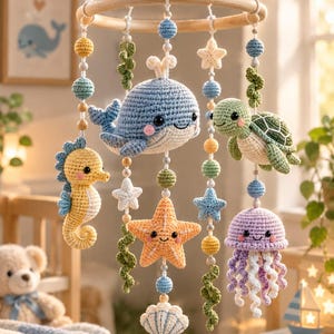 May include: A hanging nursery mobile featuring crocheted sea creatures including a blue whale, green turtle, yellow seahorse, orange starfish, and purple jellyfish, suspended from a circular wooden frame with small crocheted spheres and stars.
