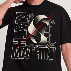 Może przedstawiać: Czarny t-shirt z grafiką i napisem MATH AIN'T MATHIN'. Wzór zawiera białą wstęgę Mobiusa, czerwoną linię ukośną, symbol pi, znak pierwiastka kwadratowego oraz geometryczne elementy liniowe wykonane białą farbą drukarską.