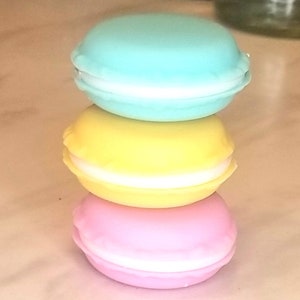 Puede incluir: Pila de tres macarons de color pastel. El macaron de arriba es azul claro, el macaron del medio es amarillo y el macaron de abajo es rosa.
