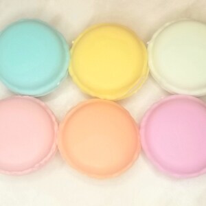 Puede incluir: Seis macarons de color pastel, dispuestos en fila. Los macarons son azul claro, amarillo, blanco, rosa, melocot&oacute;n y rosa claro.