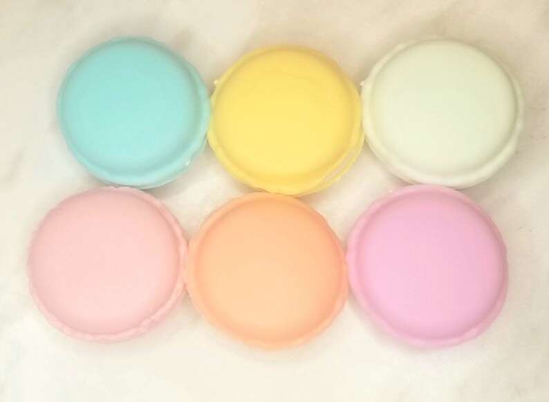 Puede incluir: Seis macarons de color pastel, dispuestos en fila. Los macarons son azul claro, amarillo, blanco, rosa, melocot&oacute;n y rosa claro.